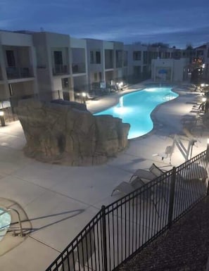 Ein Pool mit Felsen, umgeben von einem Zaun und Gebäuden.