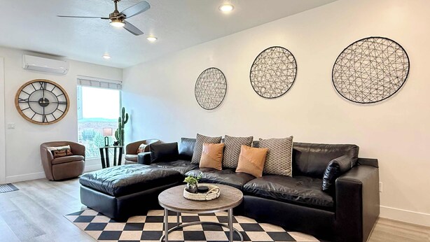 A modern living room with a black leather sectional sofa, a round coffee table, and a checkered floor.