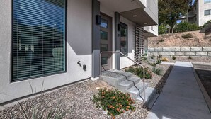 A modern building with a large window, a staircase, and a stone retaining wall.