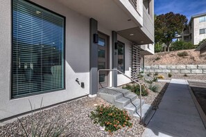 A modern building with a large window, a staircase, and a stone retaining wall.