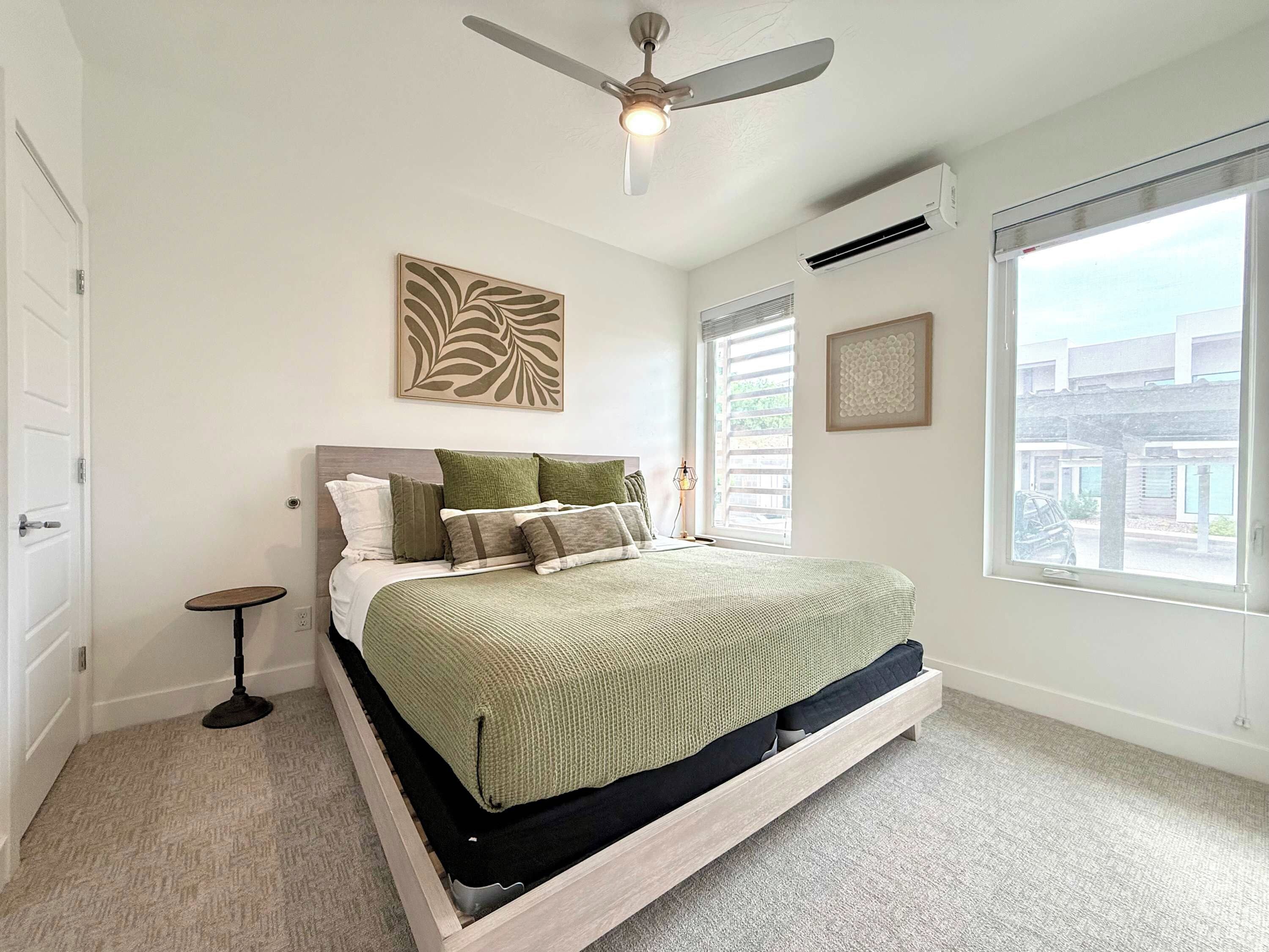 A bedroom with a bed, a ceiling fan, a window, and a door.