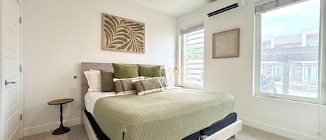 A bedroom with a bed, a ceiling fan, a window, and a door.
