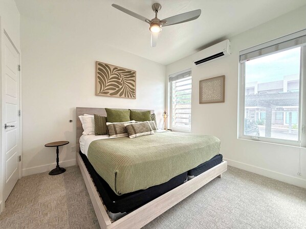 A bedroom with a bed, a ceiling fan, a window, and a door.
