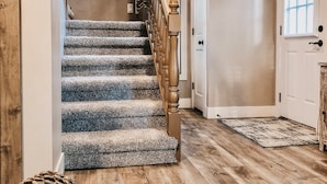 Eine Treppe mit Teppichstufen und Holzwangen, die zu einer Tür mit Fenster führt.