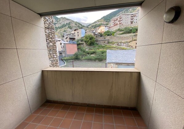 A small, enclosed balcony with a view of a hillside village.