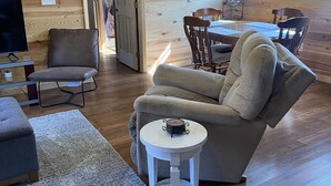 A cozy cabin interior with a wooden interior, a sofa, a dining table, and a TV.
