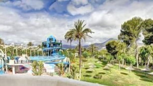 Un resort con parque acuático, palmeras y montañas al fondo.