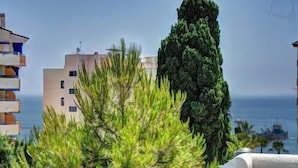 Un edificio costero con balcones que dan al mar, rodeado de vegetación.