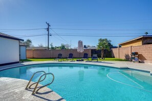 A swimming pool with a clear blue water, surrounded by lounge chairs and a brick wall. - Relax Poolside: Central Group Getaway in Mesa! (Mesa)