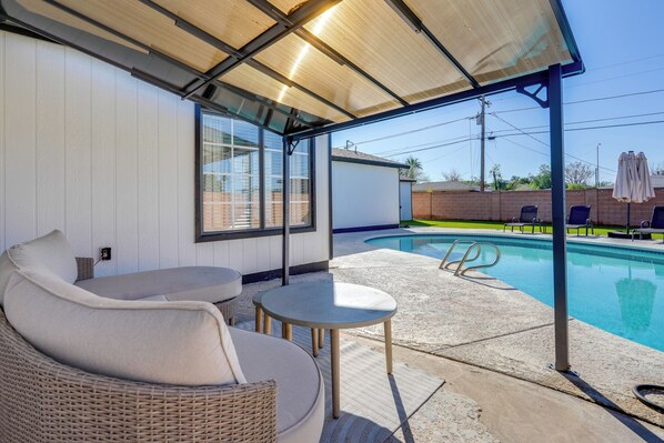 A covered outdoor seating area with a pool, wicker furniture, and a view of the pool. - Relax Poolside: Central Group Getaway in Mesa! (Mesa)