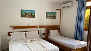 A room with two beds, a wooden headboard, a wall-mounted air conditioner, and two paintings. - Stunning 3-Bed Apartment in Kribi (Kribi)