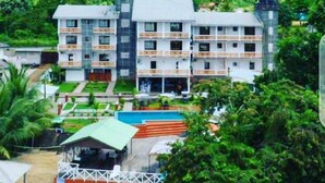 A multi-story hotel with a pool area, surrounded by lush greenery. - Stunning 3-Bed Apartment in Kribi (Kribi)