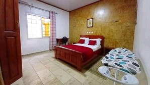 Un dormitorio con cama, un escritorio pequeño, una silla y una ventana con cortinas.