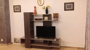 Una sala de estar con un mueble de entretenimiento de madera oscura, un televisor de pantalla plana y un jarrón con flores amarillas.