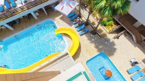 Ein Poolbereich auf dem Dach mit einem großen Pool, einem kleineren Pool und einer Wasserrutsche.