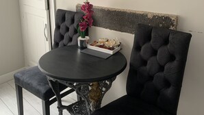Un coin repas avec une table ronde, deux chaises rembourrées, une petite plante en pot et une horloge encadrée accrochée au mur.