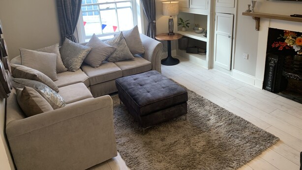 Un salon moderne avec un canapé, un pouf et une cheminée.