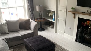 Un salon moderne avec un canapé, un pouf et une cheminée.