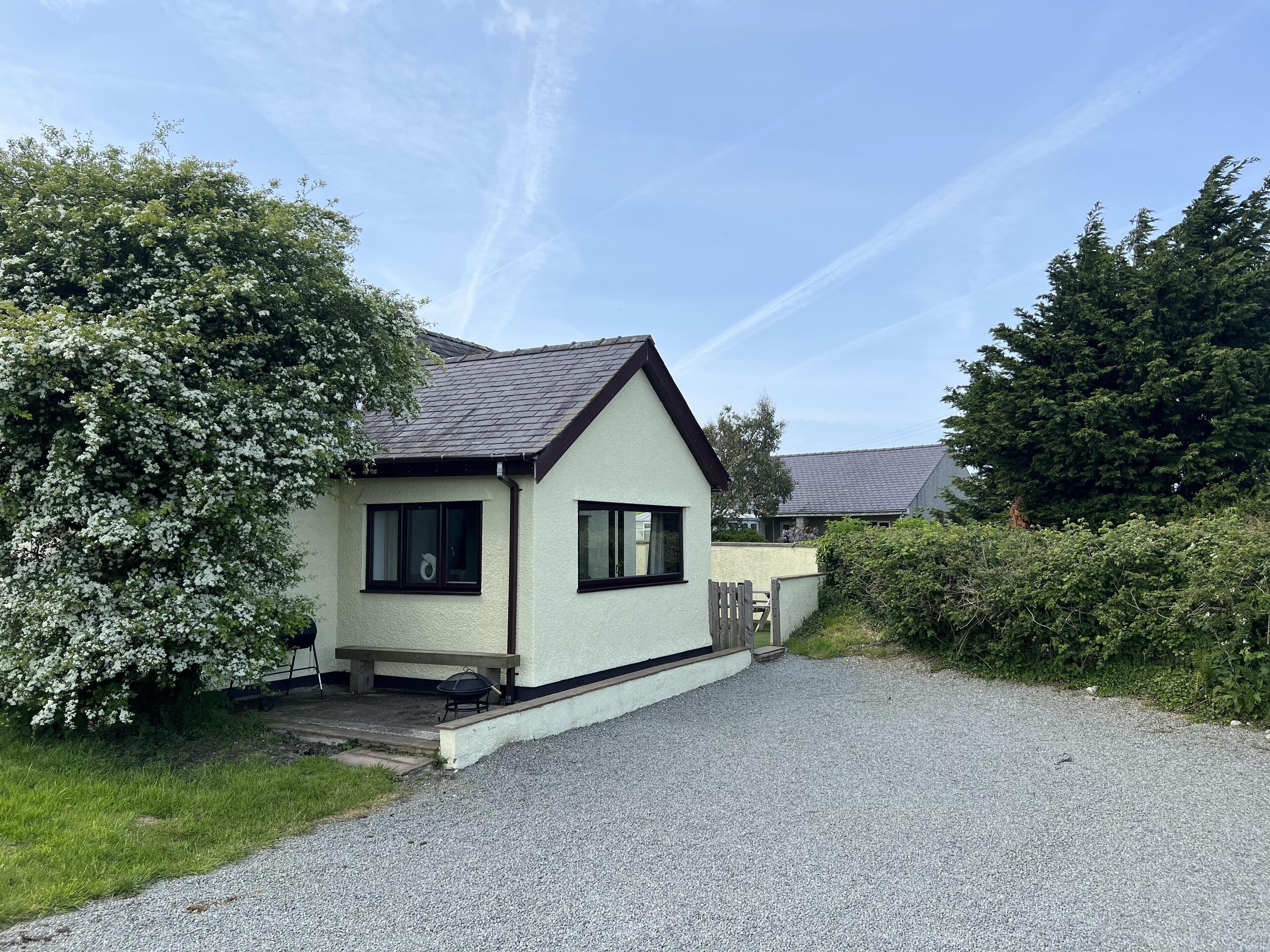 Ein kleines, eingeschossiges Haus mit Kiesweg und Garten.