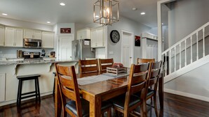 A dining area with a wooden table, chairs, and a hanging light fixture.