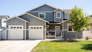 A two-story house with a garage, a front porch, and a small tree in the front yard.