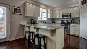 A kitchen with white cabinets, a granite countertop, stainless steel appliances, and a window.