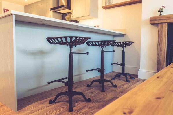 A kitchen with a white countertop and two black bar stools with metal bases.