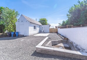 Une maison blanche avec une allée en gravier et un petit jardin.