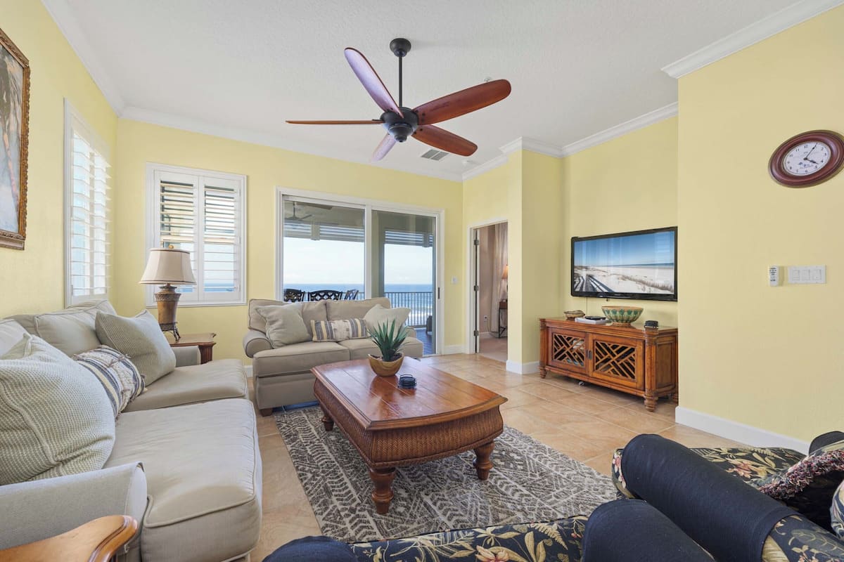 A living room with a ceiling fan, a sofa, a coffee table, and a television.