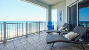 A balcony with two wicker lounge chairs, a small table, and a blue chair. A sign on the wall reads "The House." - Cinnamon Beach 7 by Distinctive Beach Rentals (Palm Coast)