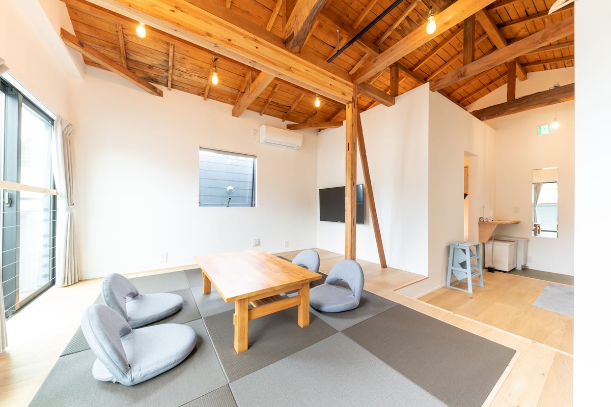 Una habitación con techo de madera, una mesa, dos sillas, un televisor y una ventana.