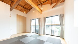 A spacious room with a high ceiling, large windows with curtains, and a tatami mat floor. - Gora Base A (Hakone)