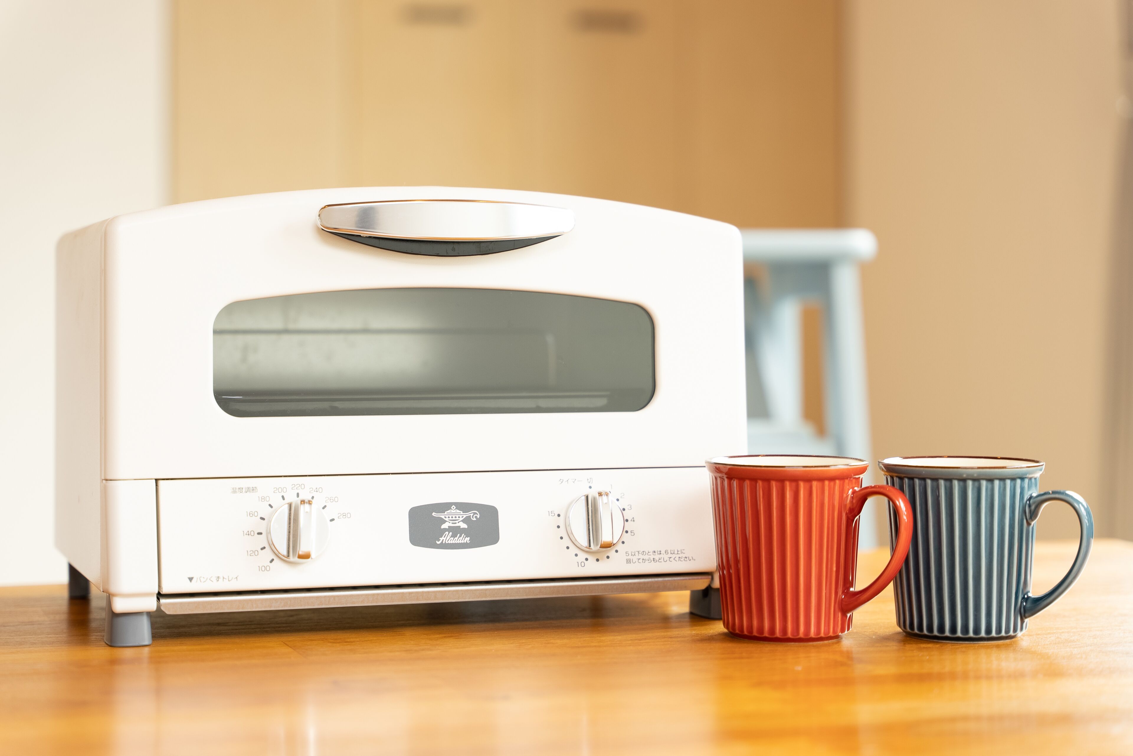A white toaster oven with two mugs beside it.