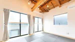 A spacious room with large windows, a wooden ceiling, and a tatami mat floor. - Gora Base A (Hakone)