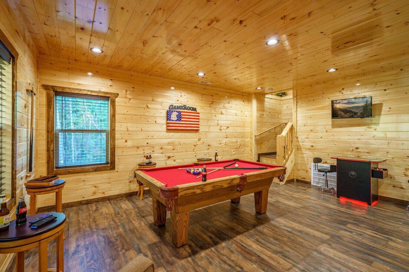 Een kamer met houten lambrisering, een pooltafel, een bar en een trap.