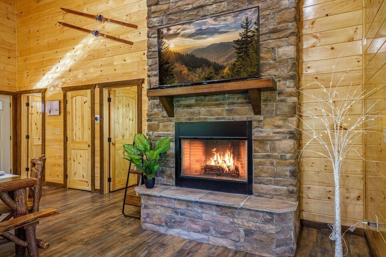 A cozy room with a stone fireplace, wooden walls, and a view of the mountains.
