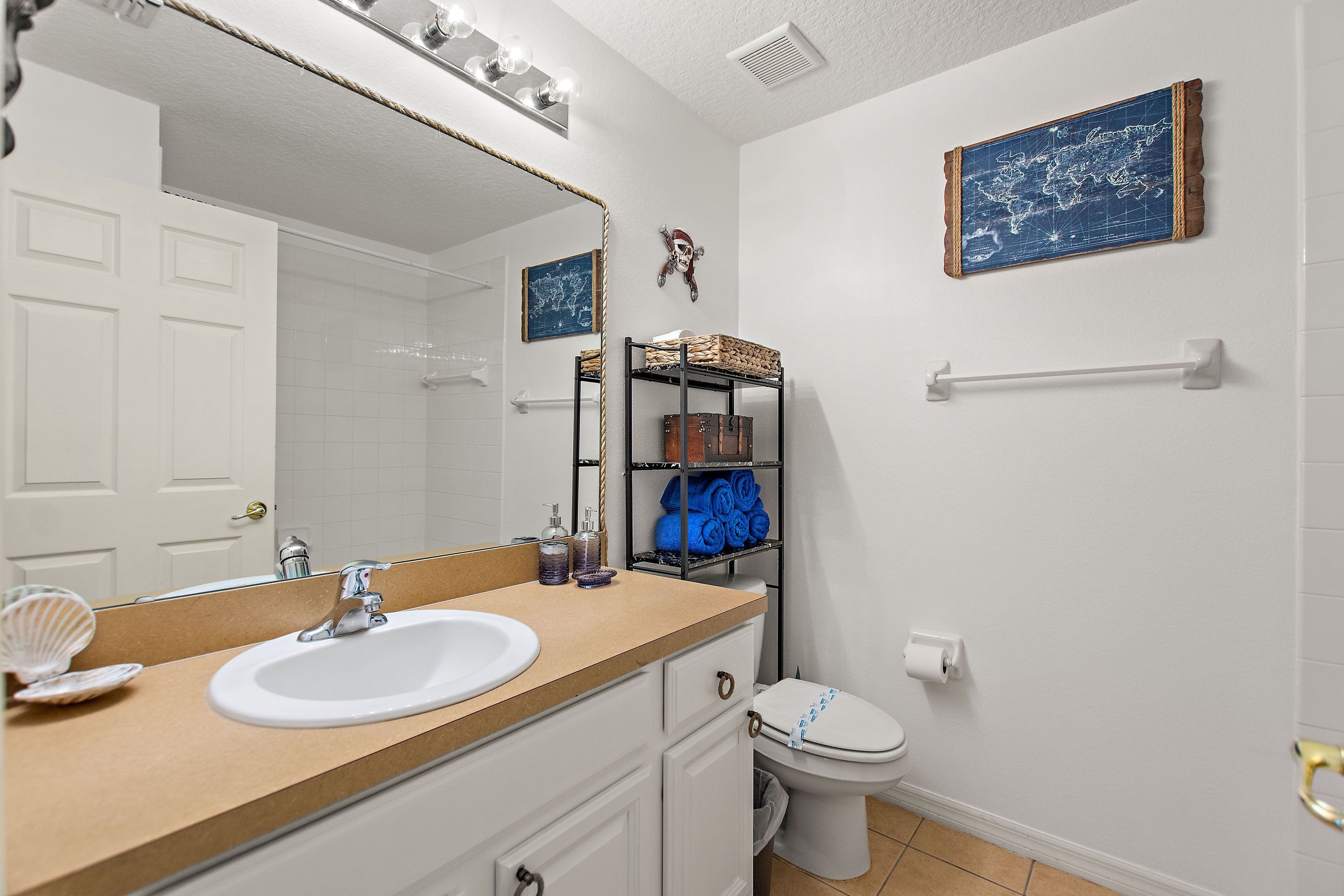 A bathroom with a white sink, mirror, and toilet. There are towels and toiletries on the counter.