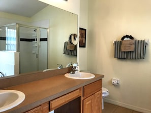A bathroom with a wooden vanity, a sink, a mirror, a towel rack, and a toilet.