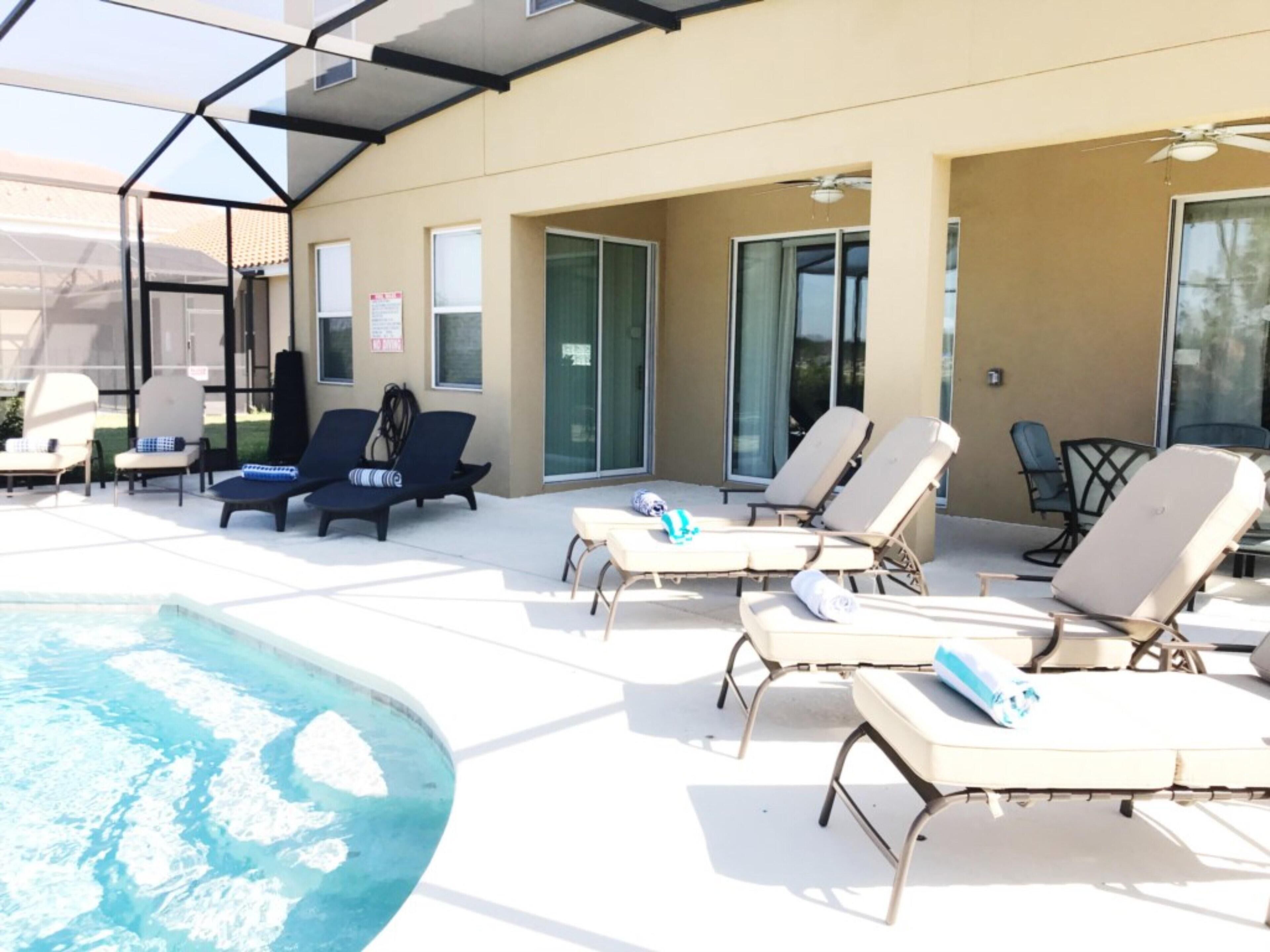 A poolside area with lounge chairs and a hot tub.
