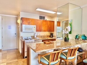 Una cocina con armarios de madera, microondas, estufa y una isla grande con sillas.