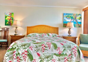 A hotel room with a bed, two nightstands, a chair, and two paintings on the walls. - Junior Suite Oceanfront #907 (Lahaina)