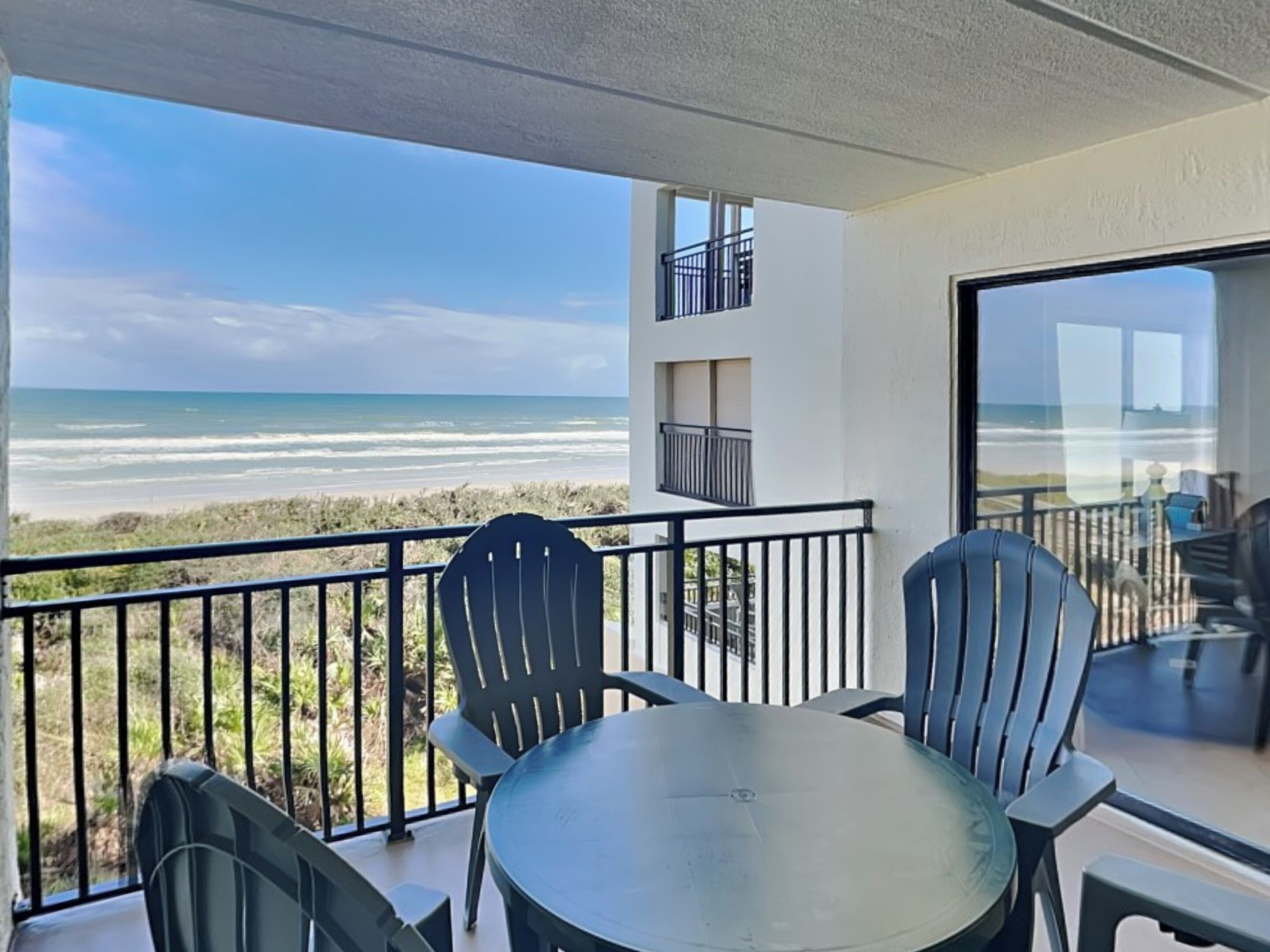 A balcony with a view of the beach and ocean.
