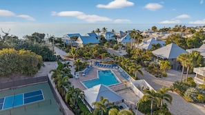 Un complexe hôtelier doté d’une piscine centrale, d’un court de tennis et offrant une vue sur la plage.