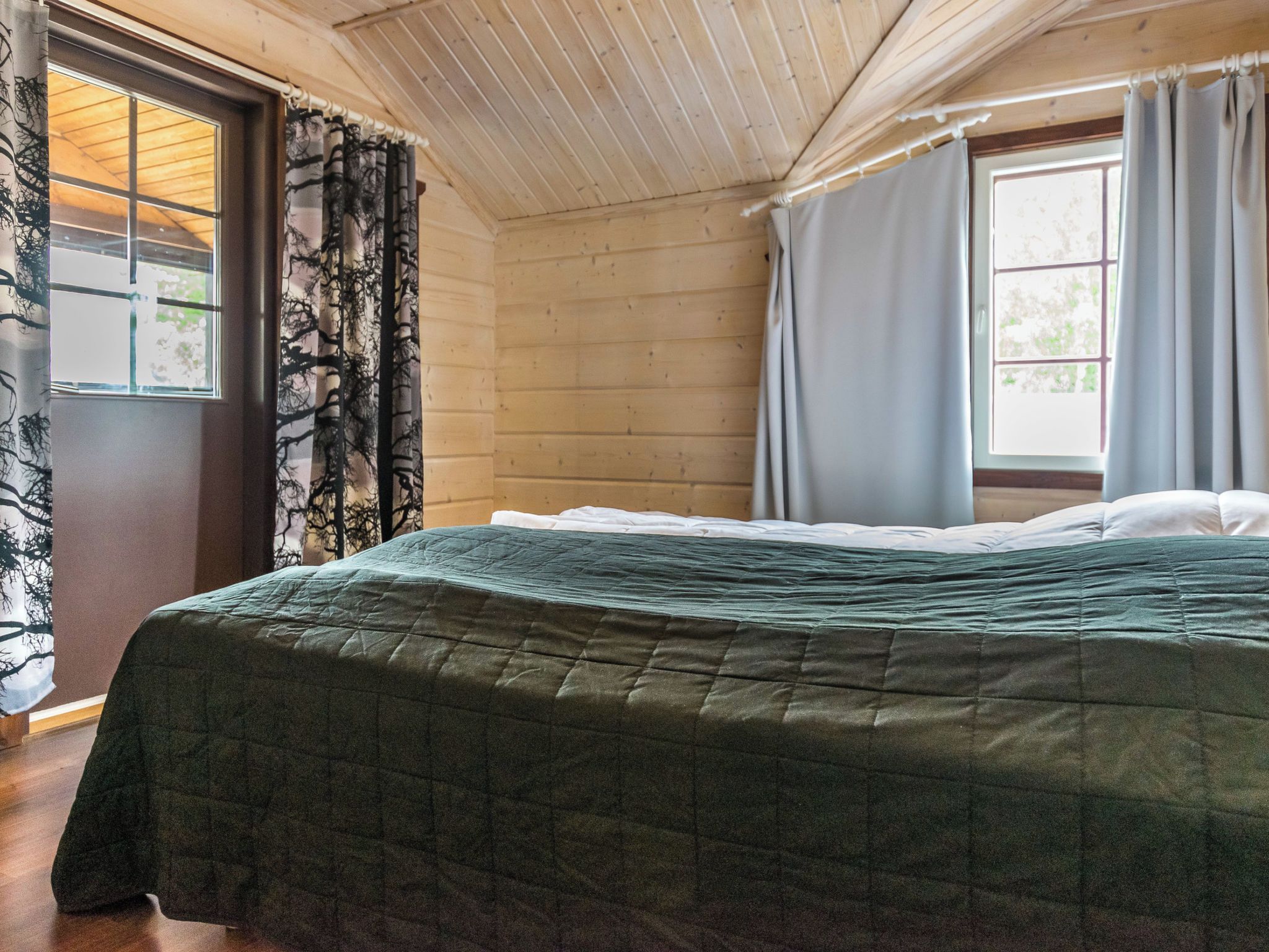 Une pièce avec un lit, des murs en bois et des fenêtres avec des rideaux.