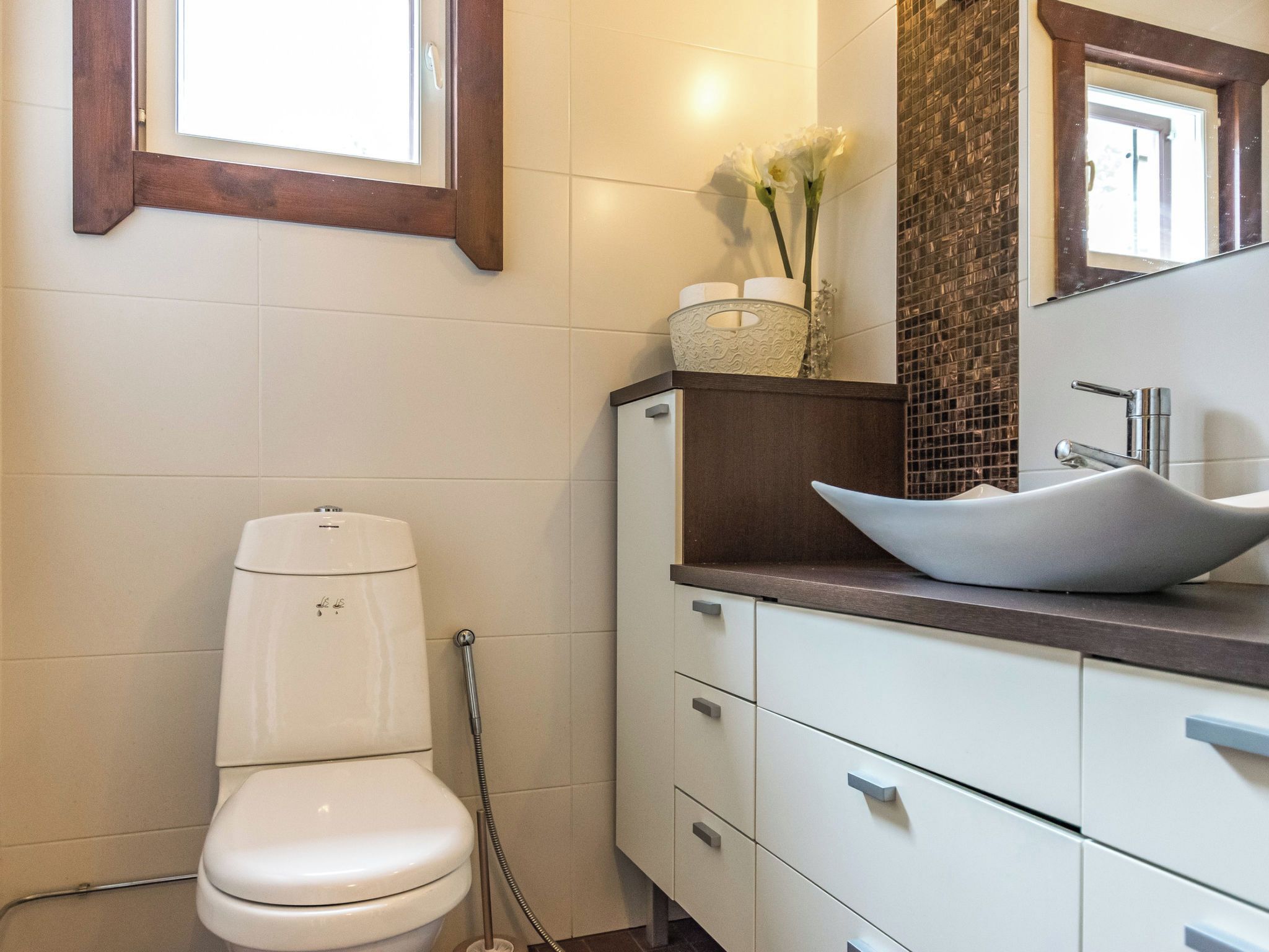 A bathroom with a toilet, a sink with a vessel basin, and a mirror.
