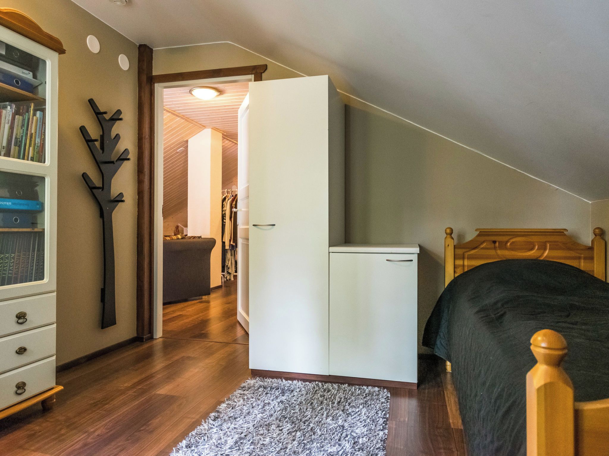 Un dormitorio con una cama, un armario, un escritorio con silla y una estantería.