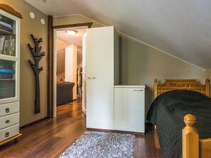 A bedroom with a bed, a wardrobe, a desk with a chair, and a bookshelf.