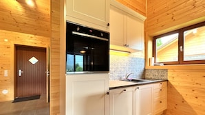 A compact kitchen with wooden walls, a built-in oven, and a window above the sink. - Chalet Stressless I by Interhome (Presseggen)