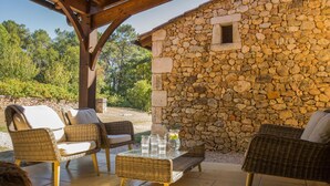 A stone building with a small window, wicker furniture, and a glass table with drinks.