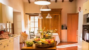 A kitchen with a central island, wooden cabinets, a dining area with a table and chairs, and a large window.